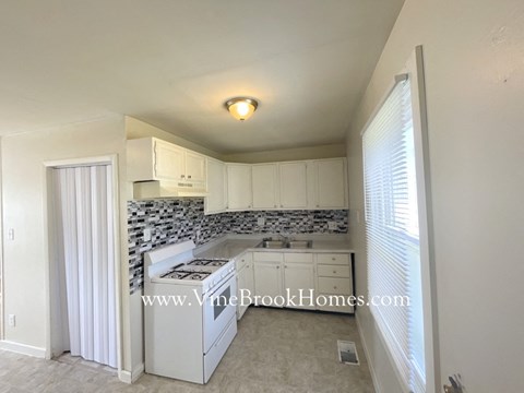 A kitchen with white cabinets and a tiled backsplash.