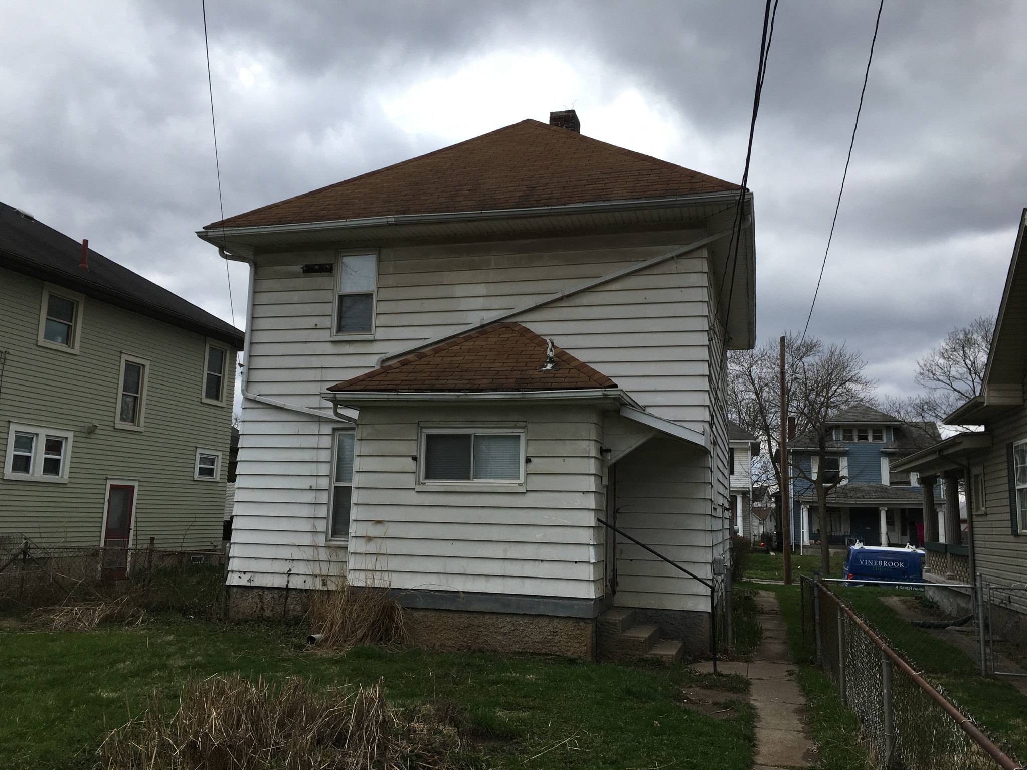 a white house with a brown roof on a sidewalk