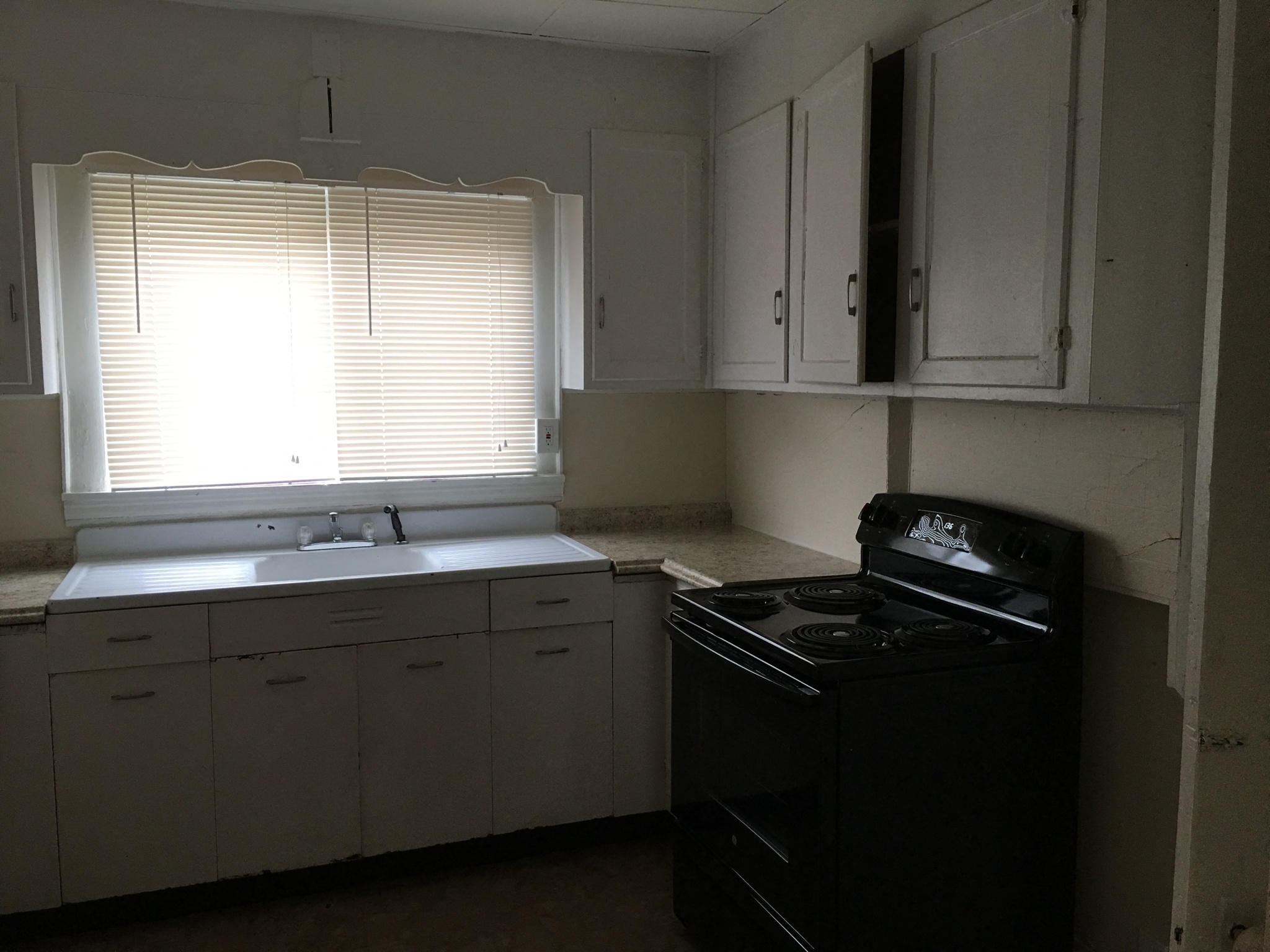 an empty kitchen with a stove and sink and a window