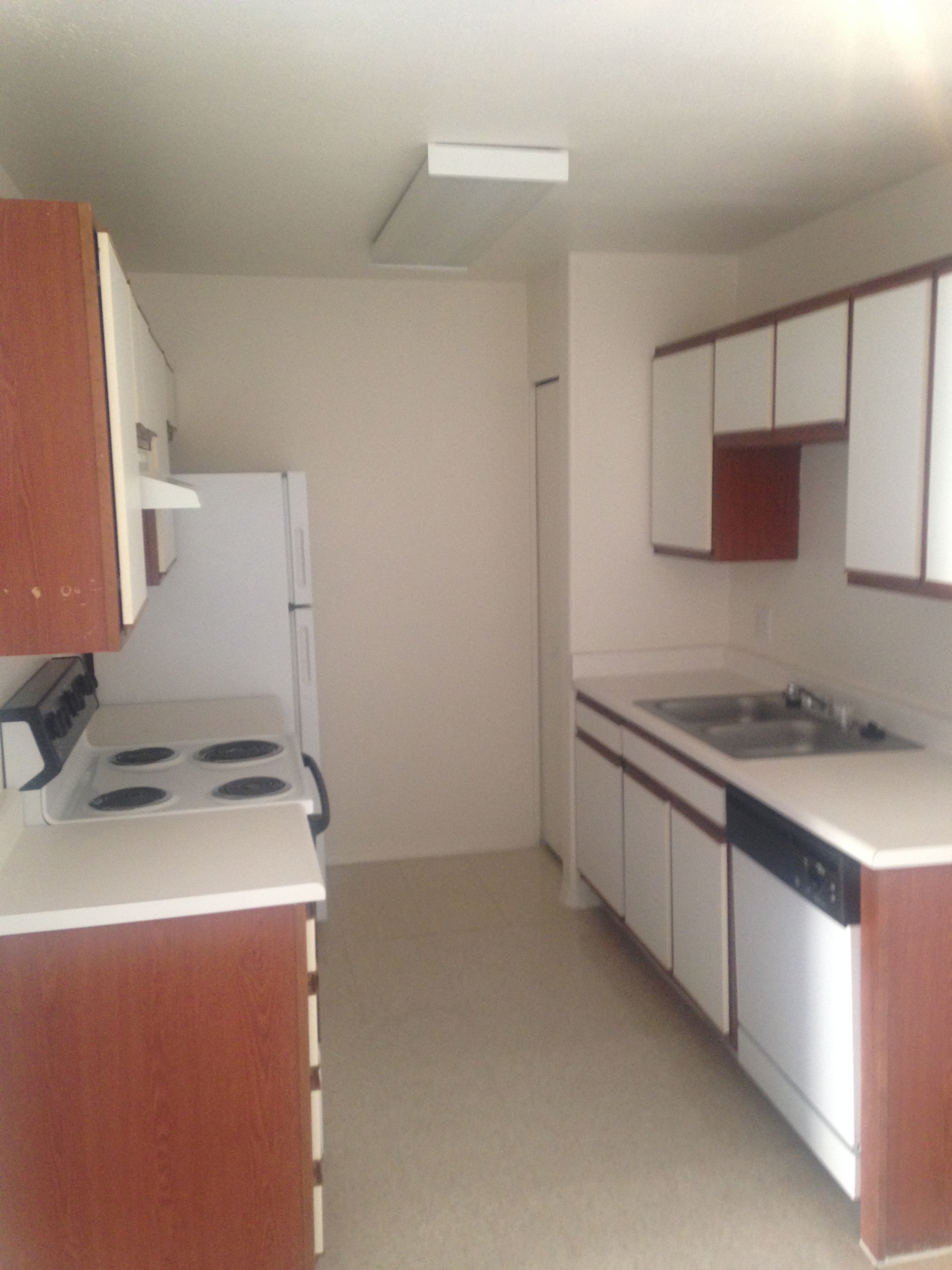 an empty kitchen with white appliances and wooden cabinets