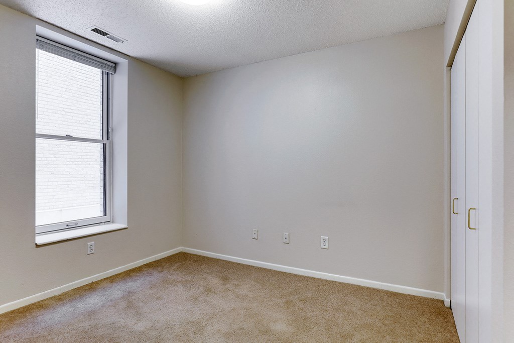 an empty room with a large window and carpet