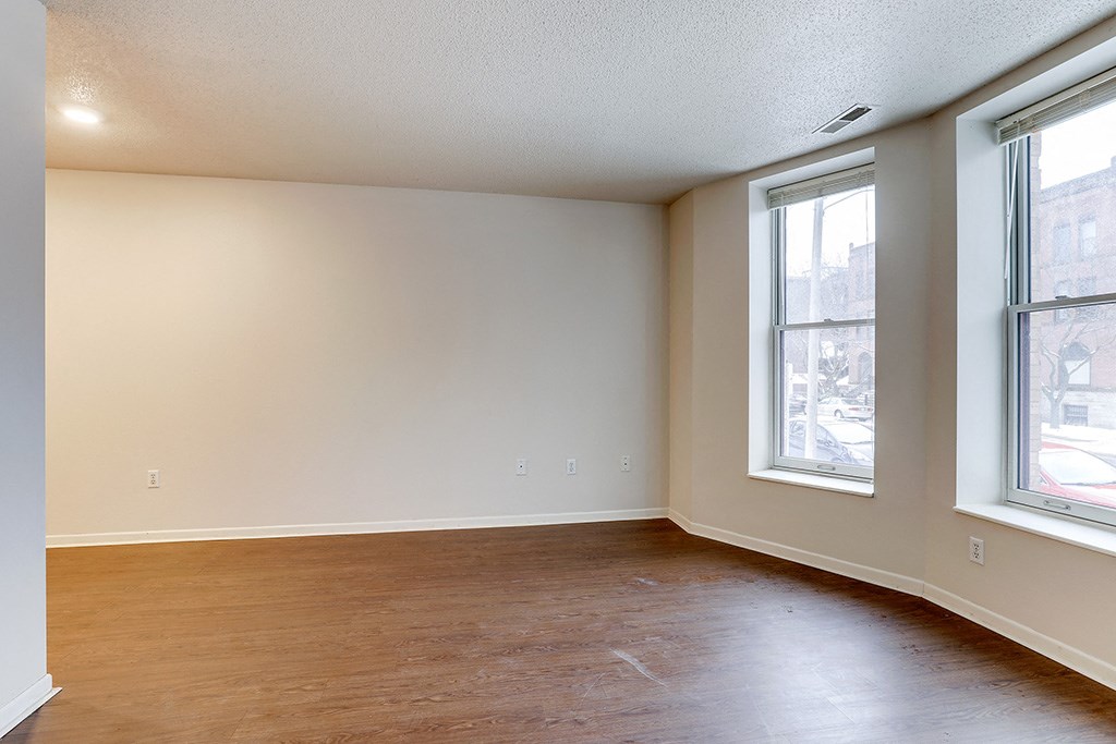 an empty living room with wood floors and two windows