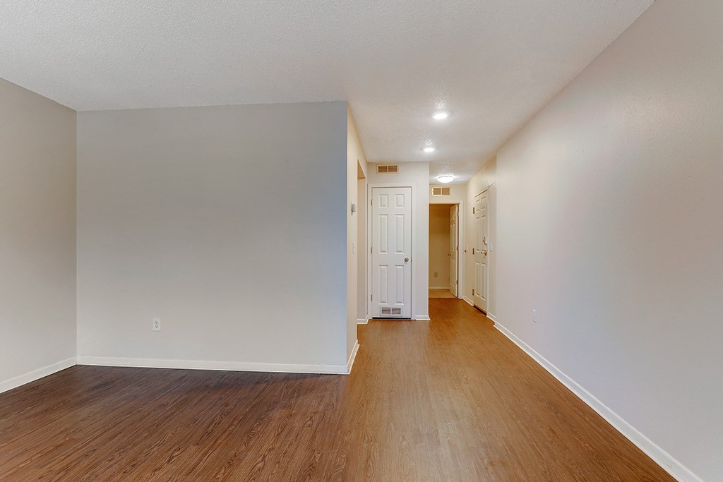 an empty living room with wood floors and white walls
