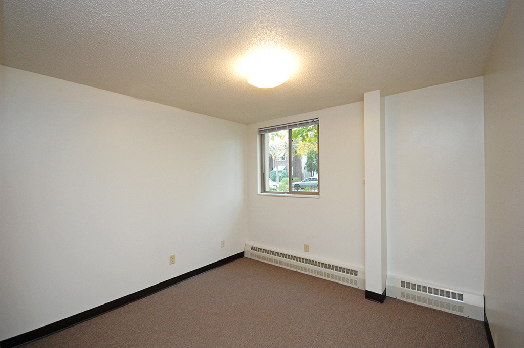 an empty living room with a window and white walls