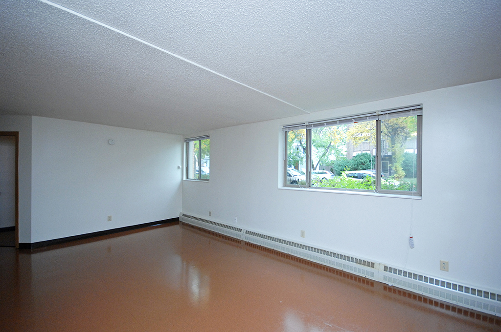 an empty room with a large window and a brown floor