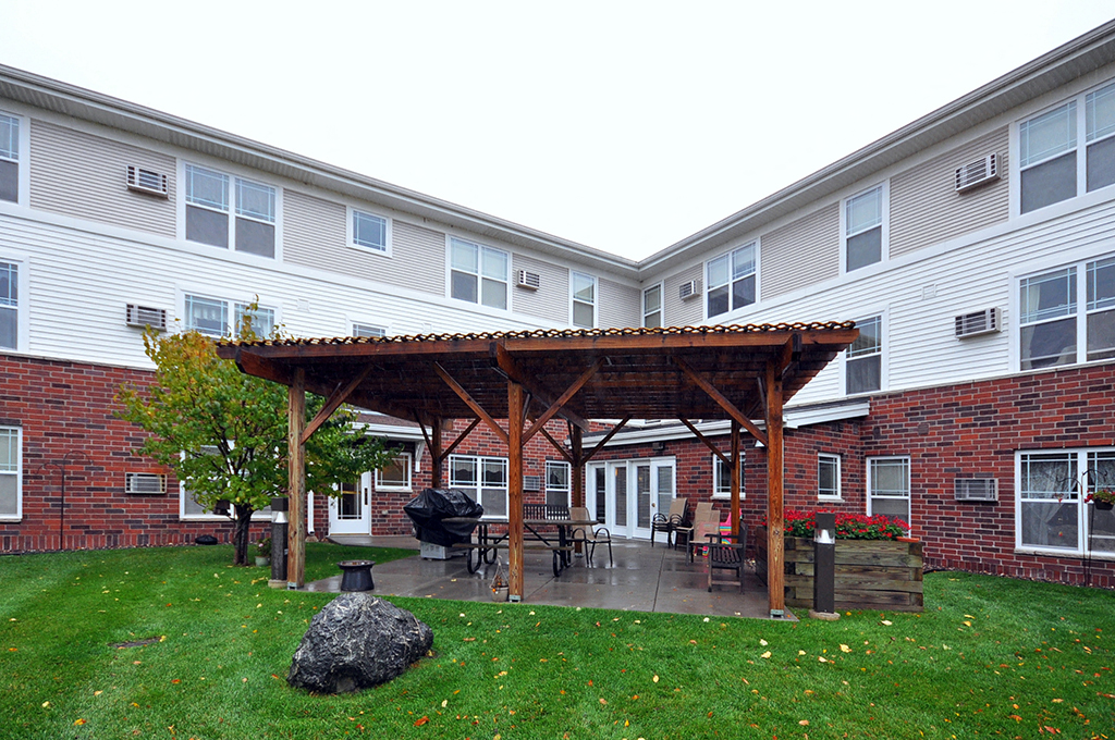 a patio with a wooden pavilion in front of an apartment building