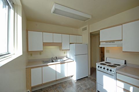 an empty kitchen with white appliances and a window