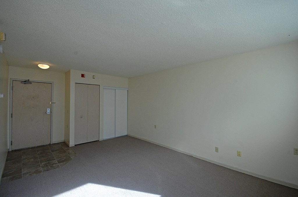 an empty living room with white walls and a door