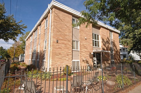 an apartment building with a fence and chairs in front of it