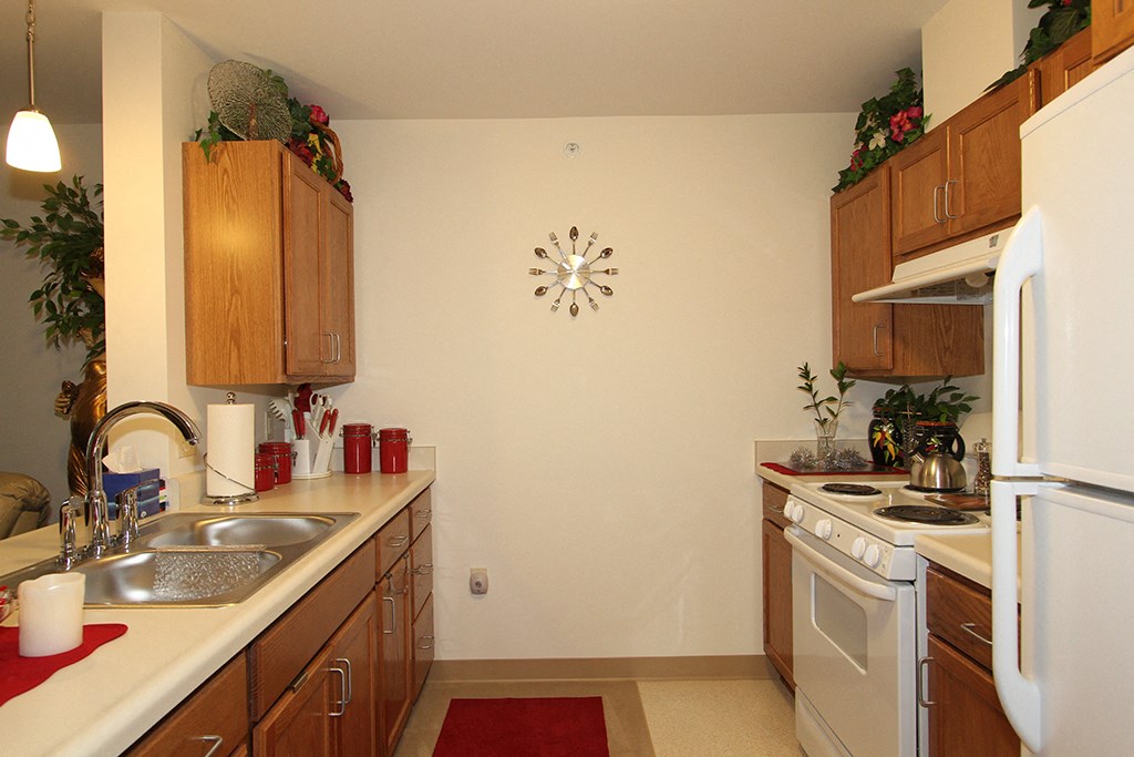 a kitchen with white appliances and wooden cabinets and a clock on the wall