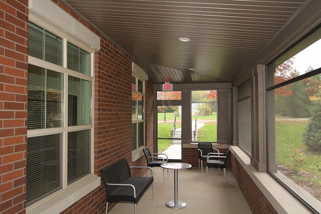 a porch of a brick building with chairs and tables