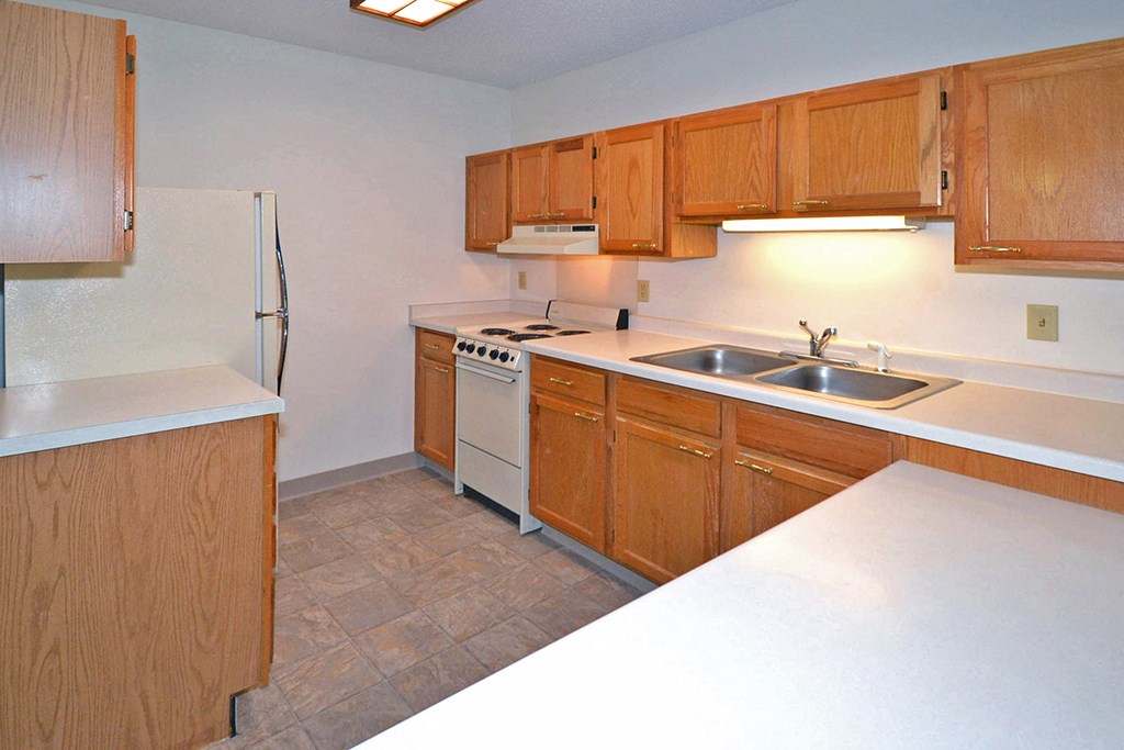 a kitchen with wooden cabinets and a sink and a refrigerator