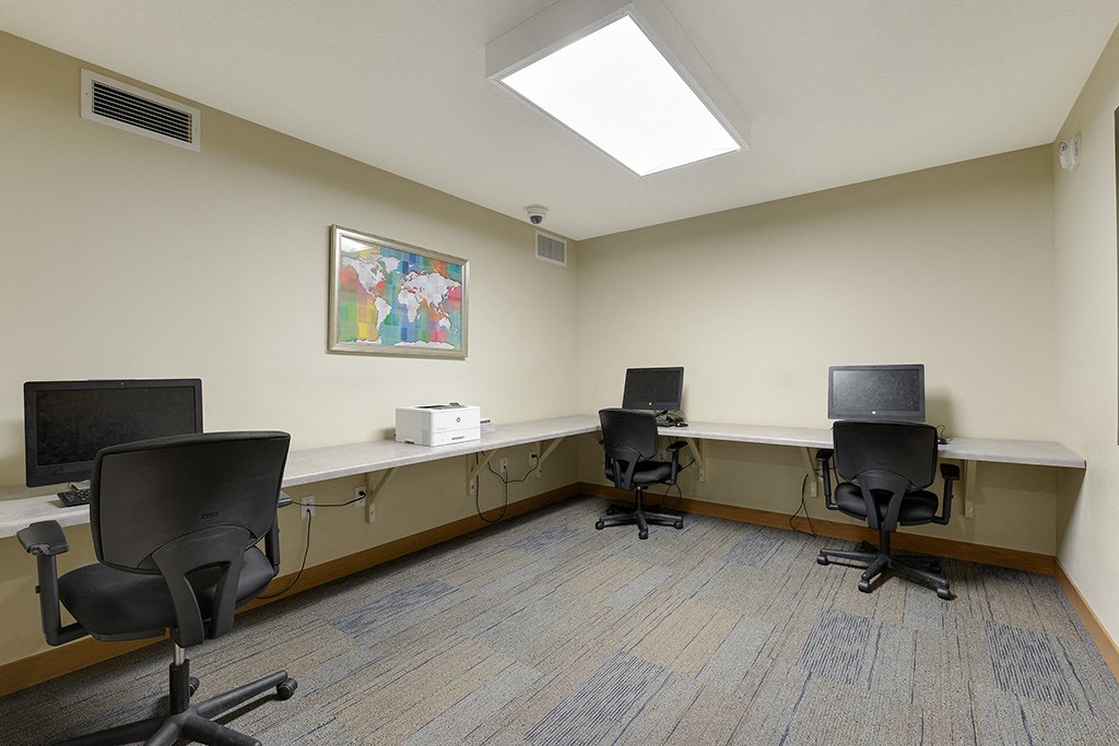 a room with three desks with computers and chairs