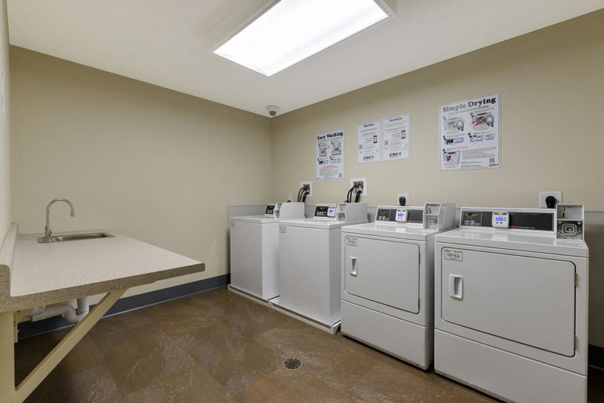 a laundry room with four washers and dryers and a table with a sink