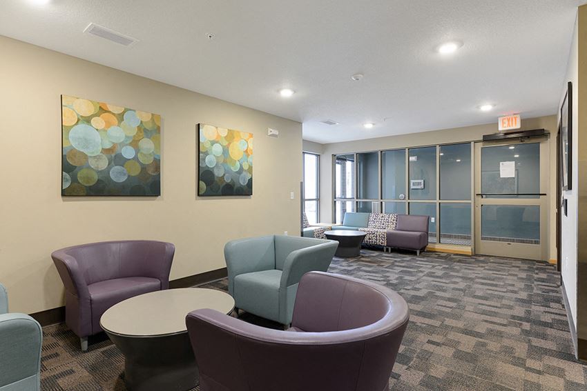 a lobby with chairs and tables and paintings on the wall