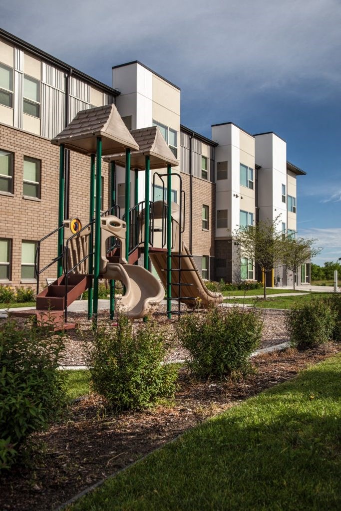 a playground with a swing set in front of an apartment building
