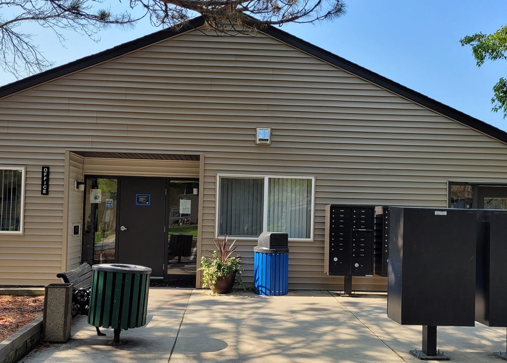 the front of a brown building with a blue trash can