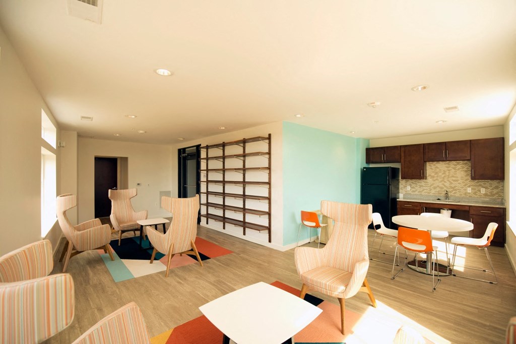 a lounge area with chairs and tables and a kitchen