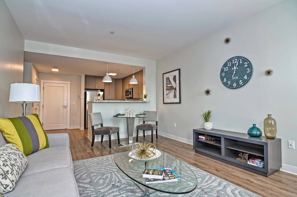 a living room with a couch and a table with a clock on the wall