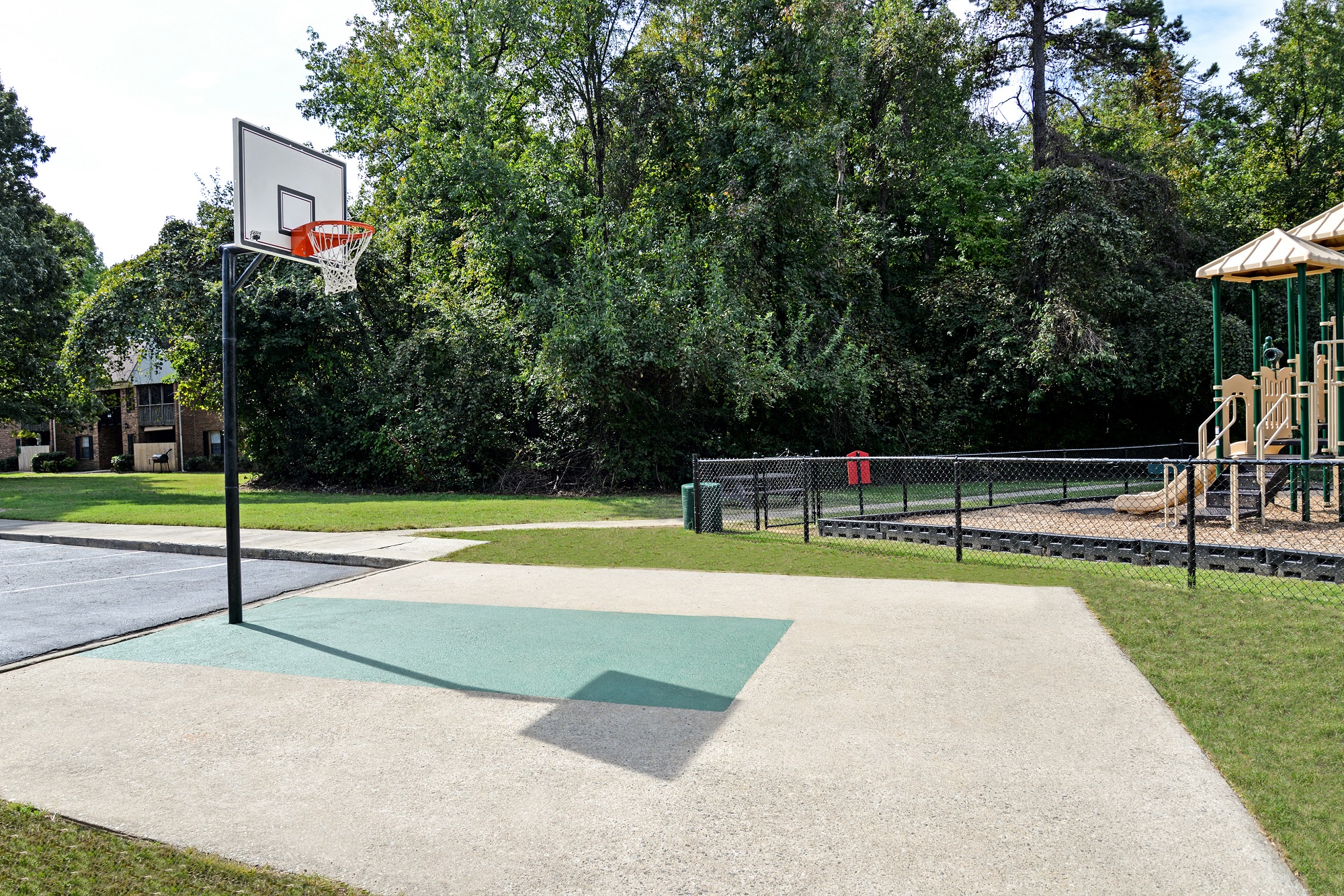 a basketball court with a playground and a swing set