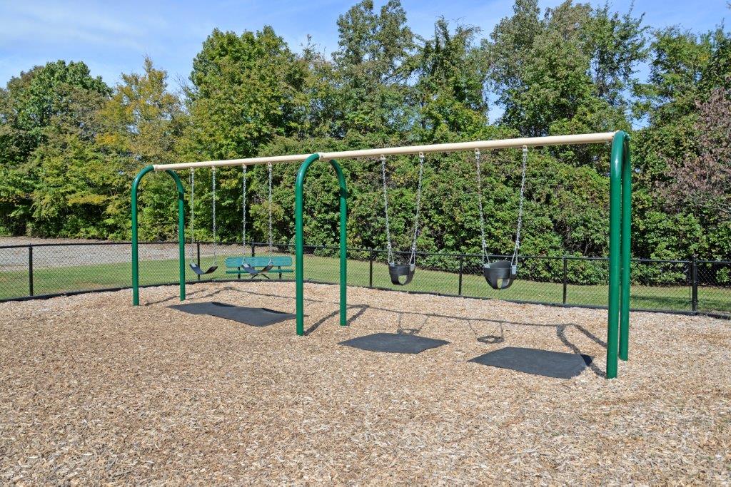 a swing set with two swings and a picnic table in a park