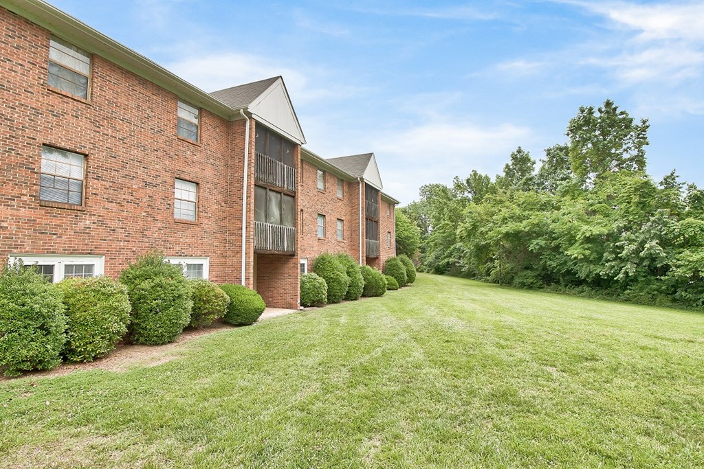 the outlook of a brick apartment building with grass and shrubs