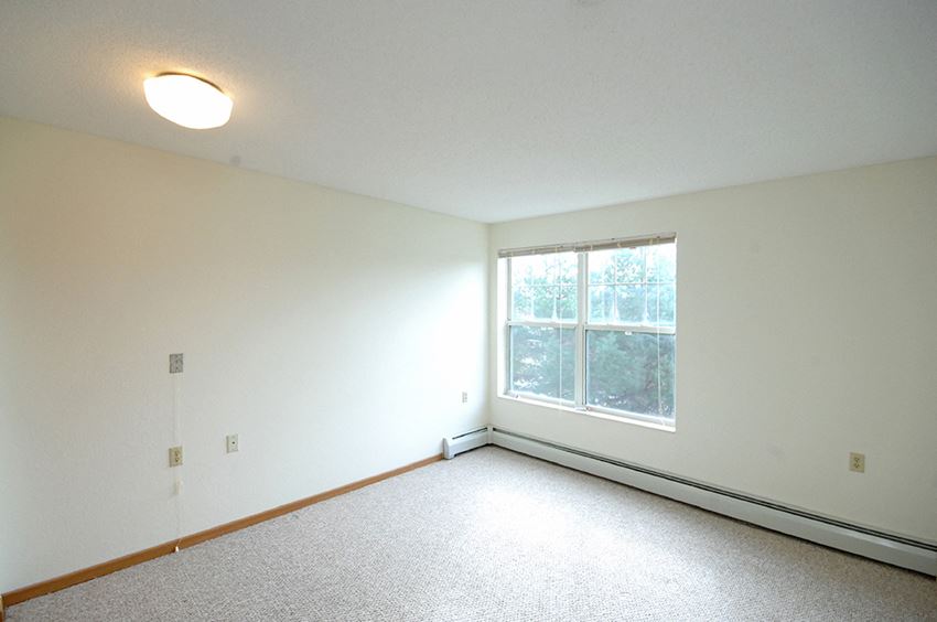 a bedroom with a large window and white walls
