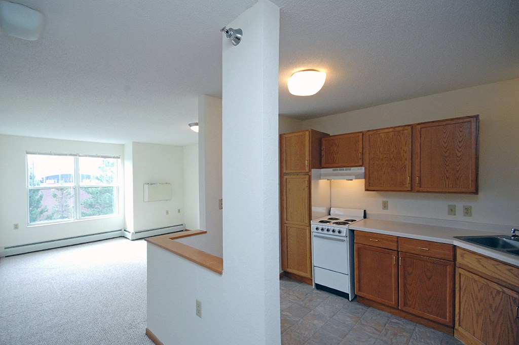 an empty kitchen with wooden cabinets and a white stove