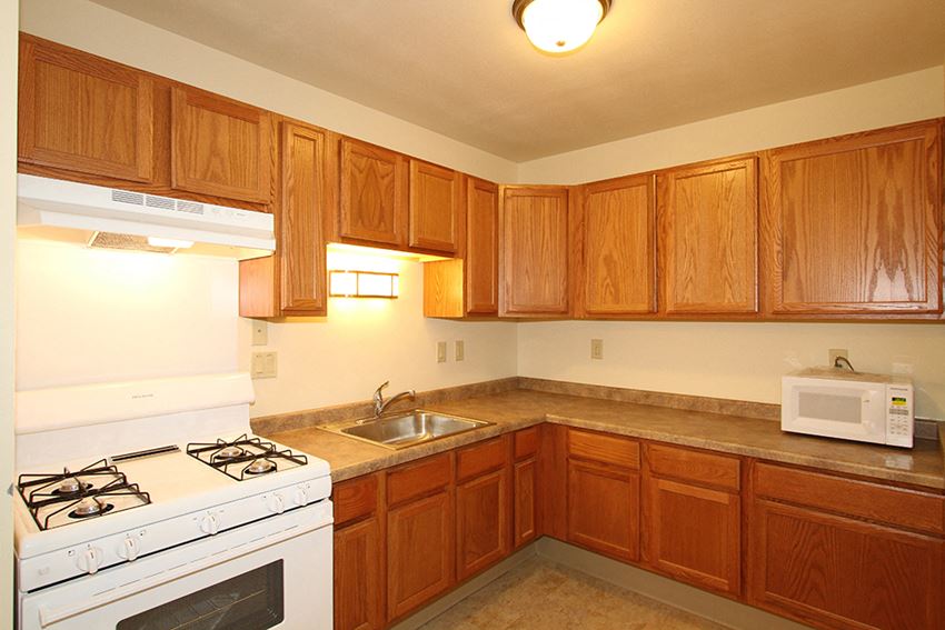 a kitchen with white appliances and wooden cabinets and a sink