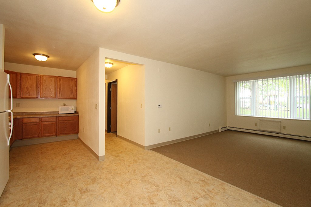 an empty living room and kitchen with a large window