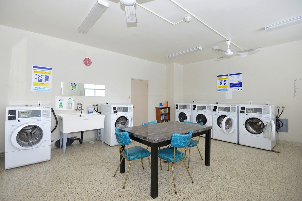 a laundry room with washing machines and a table with chairs
