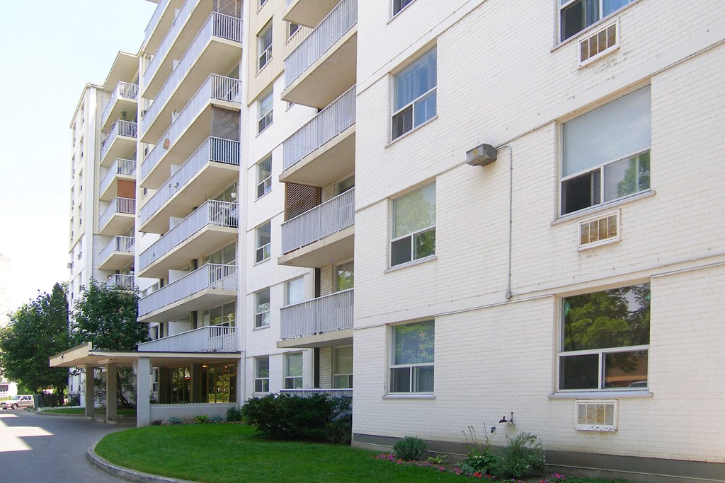 a white brick apartment building with a green lawn