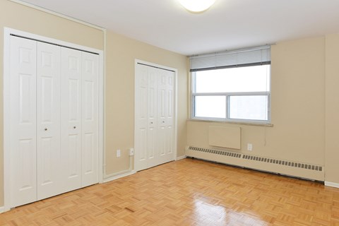 a bedroom with two closets and a window and a wood floor