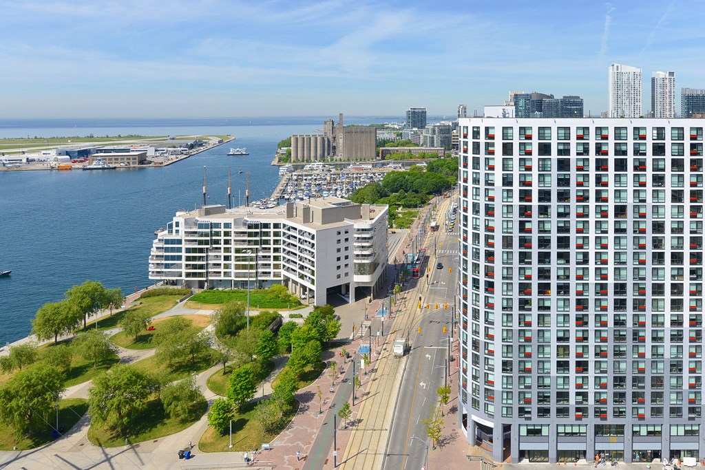 A view of a city with a large building in the foreground and a body of water in the background.