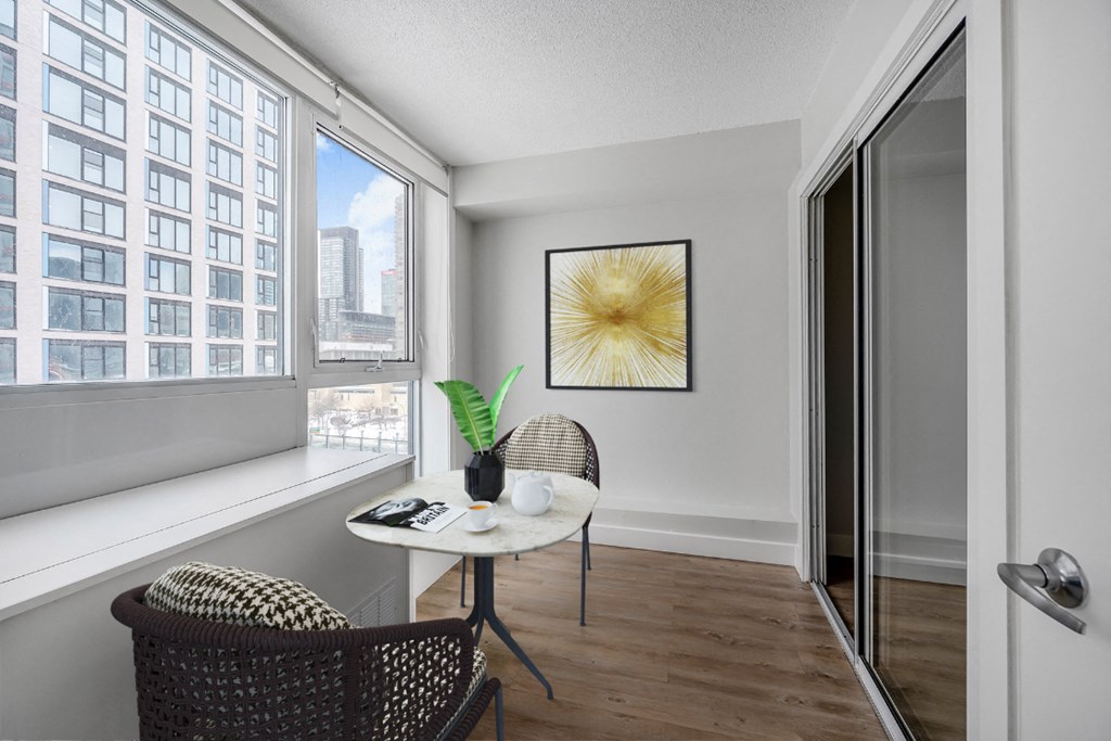 A room with a chair and a table with a vase of flowers on it.