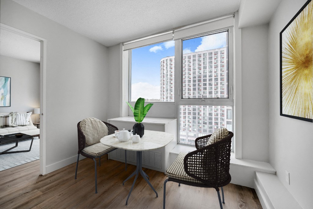 A dining room with a table and chairs and a view of a building outside the window.