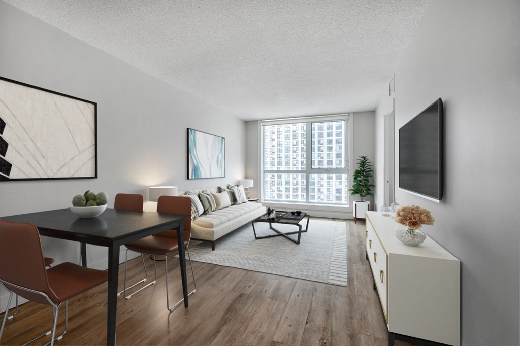 A modern living room with a black dining table and chairs, a white sofa, and a television on the wall.