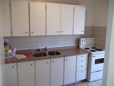A kitchen with white cabinets and a white stove.