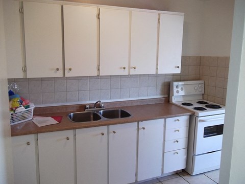 A kitchen with white cabinets and a white stove.