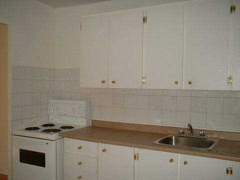 A kitchen with white cabinets and a stove top oven.