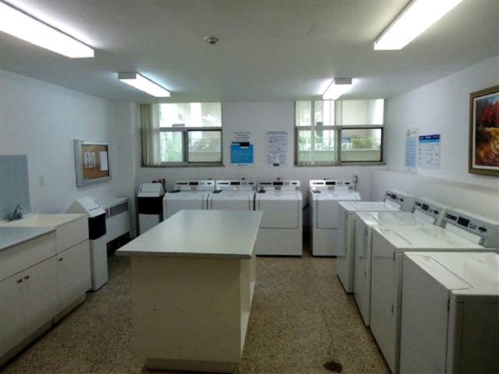 a laundry room filled with white machines and sinks