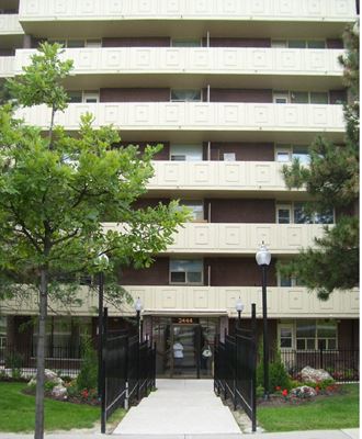the entrance to an apartment building with trees in front of it