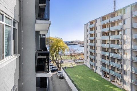 A view from a window of a residential building with a car parked on the street.