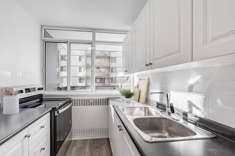 A modern kitchen with a stainless steel sink and white cabinets.