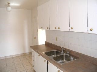 an empty kitchen with a sink and white cabinets