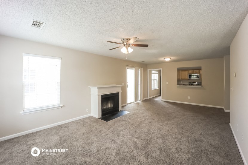 the spacious living room with fireplace and ceiling fan