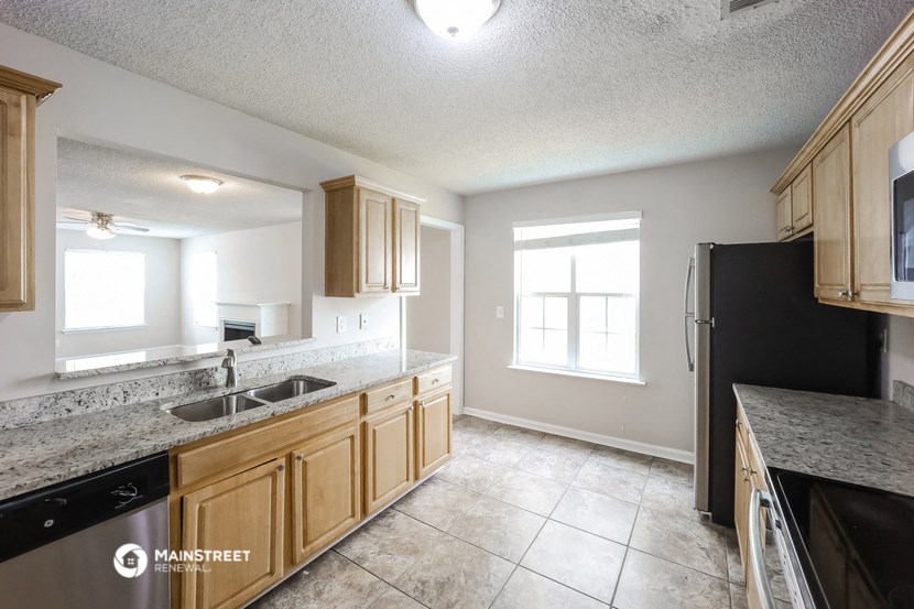 a kitchen with wood cabinets and granite counter tops and a black refrigerator