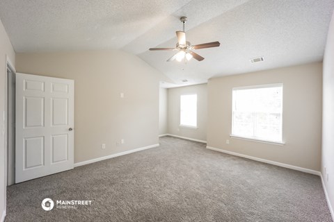 the spacious living room with carpet and a ceiling fan