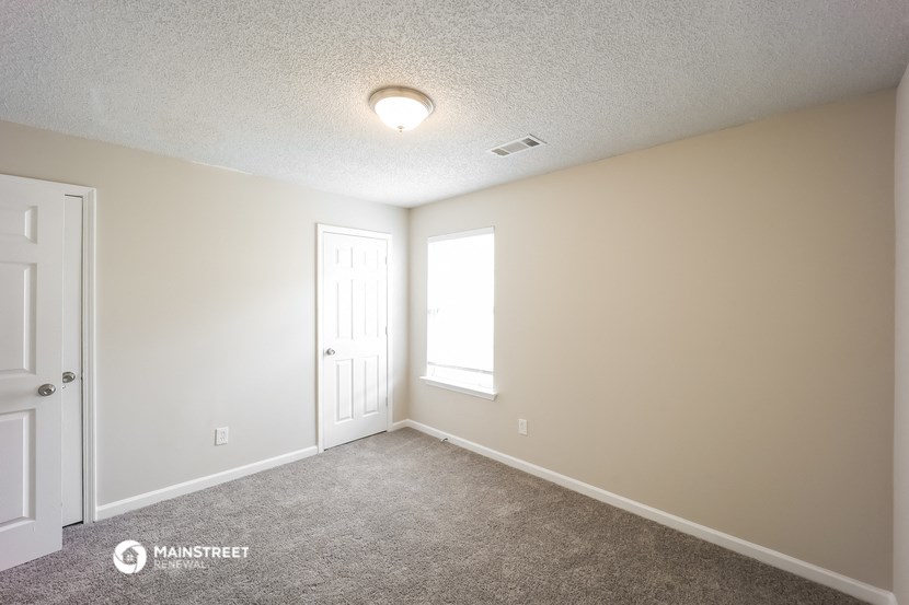 the spacious living room with carpet and a door to the bedroom