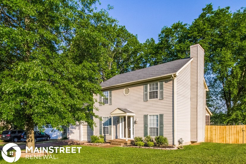 a white house with a wood fence and trees